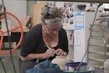 Woman trimming a bowl on a pottery wheel