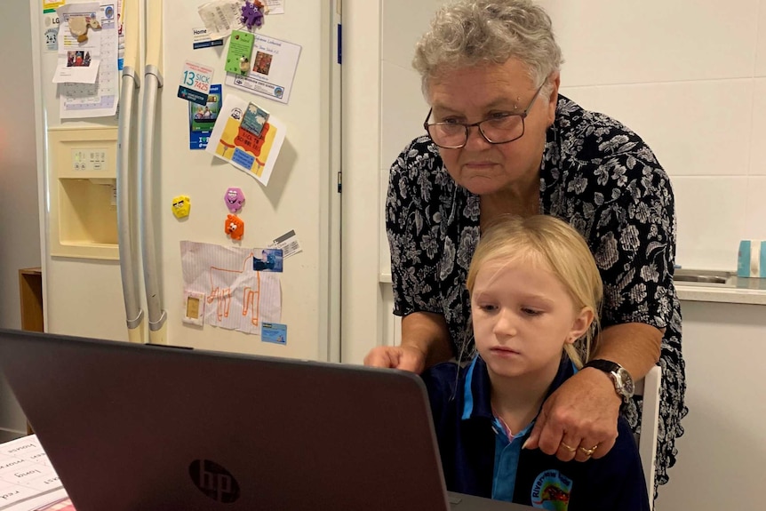 Sylvia and Sylvana look at a computer on a kitchen table.