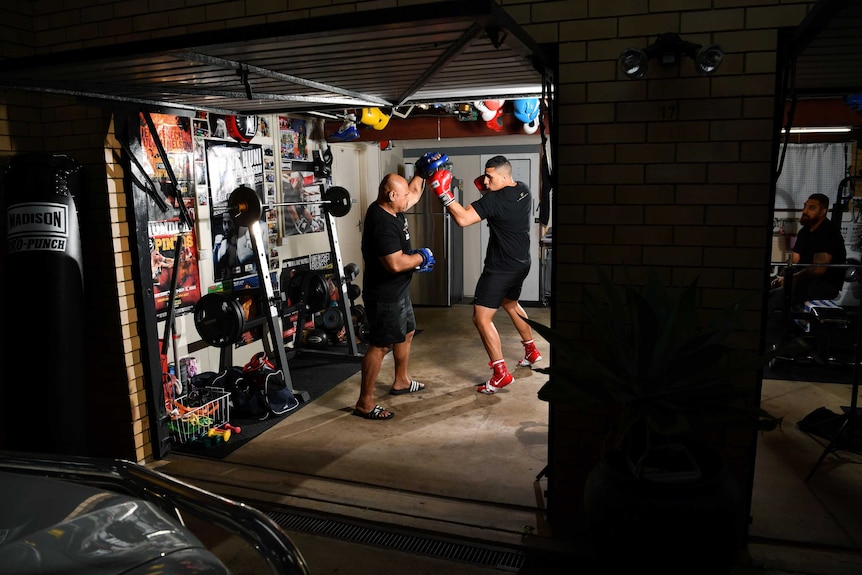 Boxer Justis Huni (right) throws an uppercut at a pad being held by his father, Rocki, as they train in their garage.