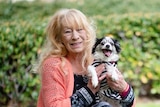 A woman holding a small black and white dog