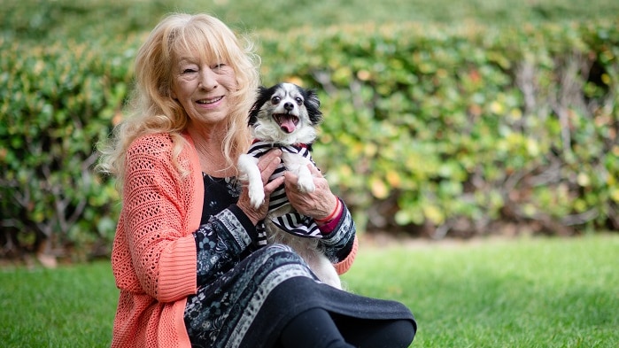 A woman holding a small black and white dog