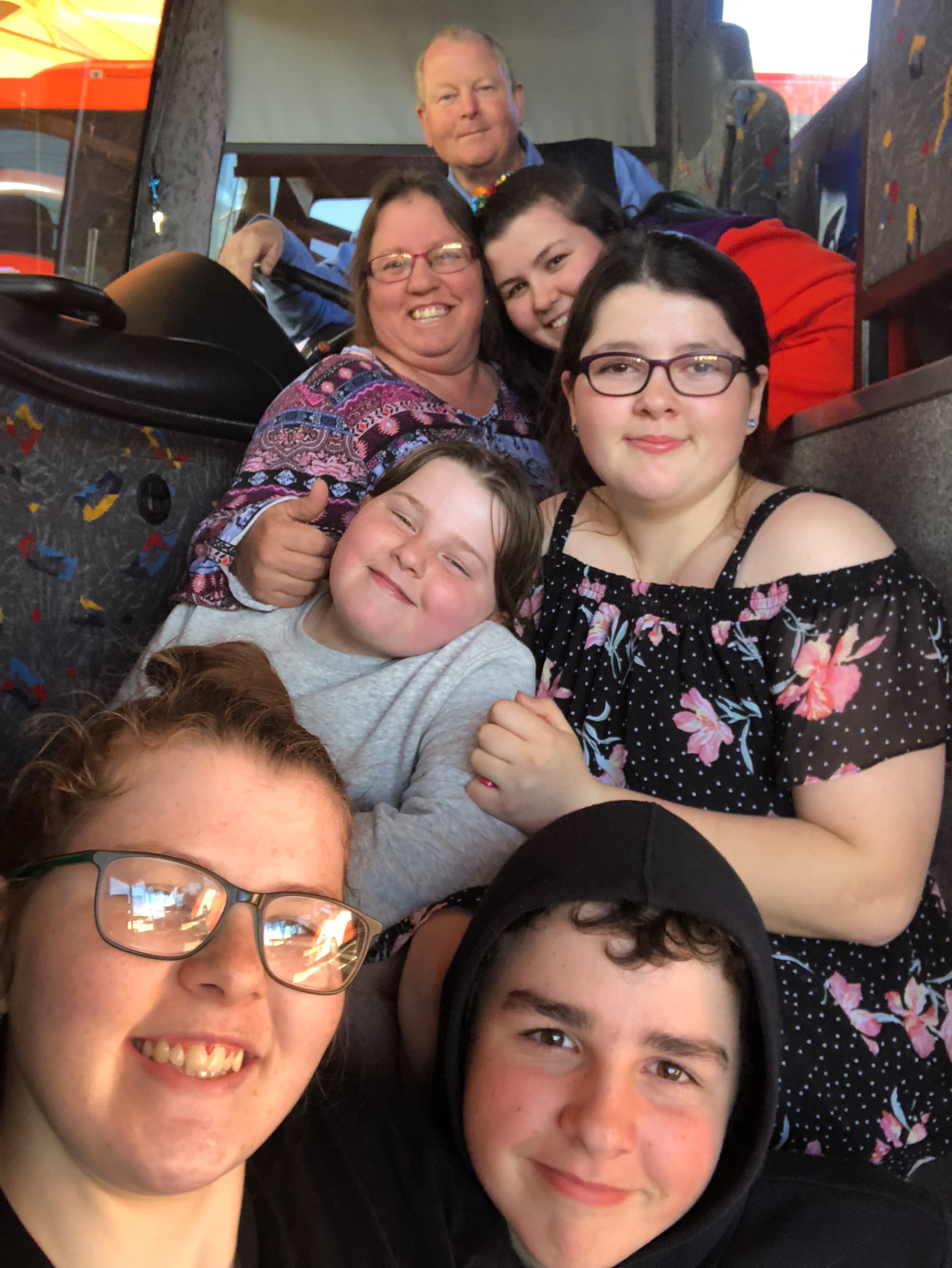 Family smiles at camera in a bus.