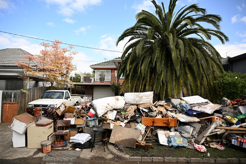 Flood damaged belongings stacked up in front of a house. 