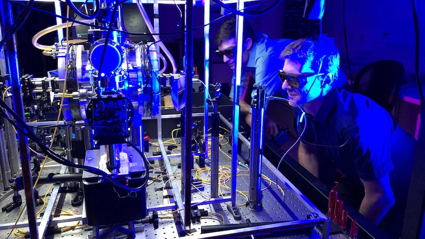 Dr Ben Sparkes and Associate Professor Martin O'Connor wearing glasses in a photonics laboratory.