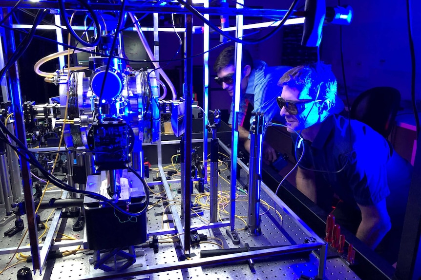 Dr Ben Sparkes and Associate Professor Martin O'Connor wearing glasses in a photonics laboratory.