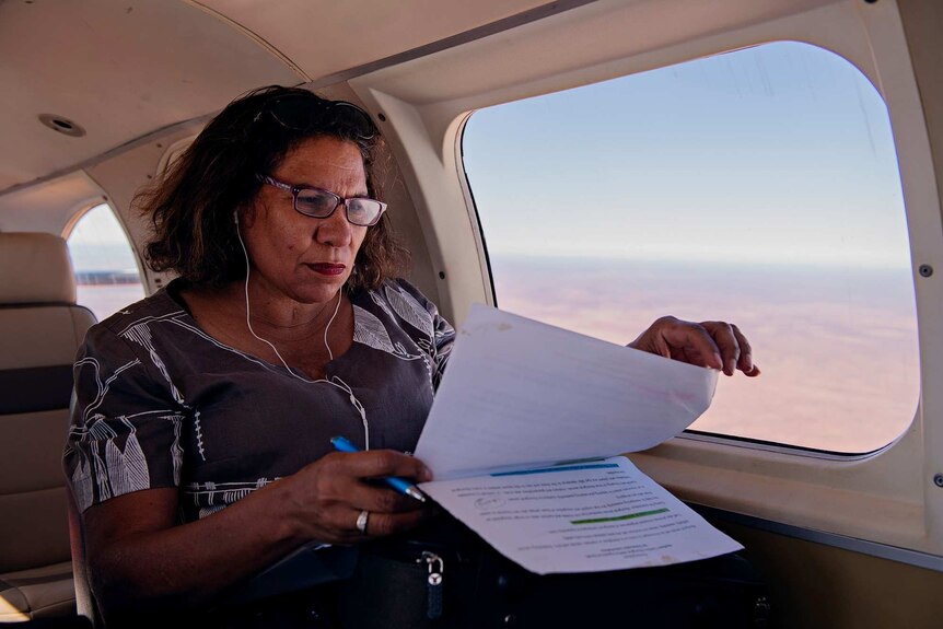Leanne Liddle flicks through documents on plane holding a pen in her hand.
