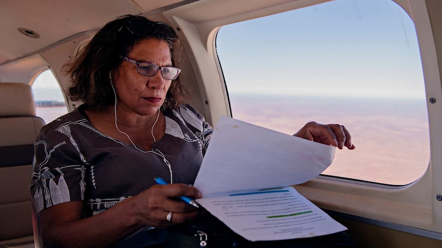 Leanne Liddle flicks through documents on plane holding a pen in her hand.