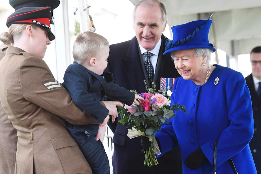 Alfie hands the Queen a bouquet of flowers to Britain's Queen Elizabeth