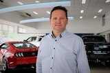 Man standing in front of cars in a showroom