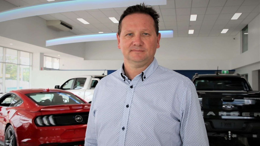 Man standing in front of cars in a showroom