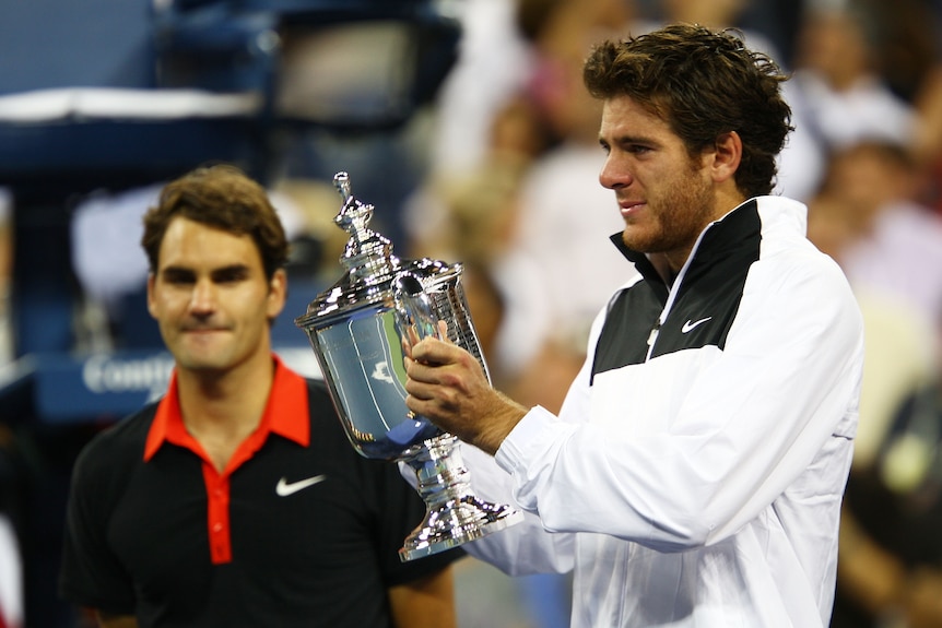 Juan Martin del Potro holds the US Open trophy in front of final opponent Roger Federer.