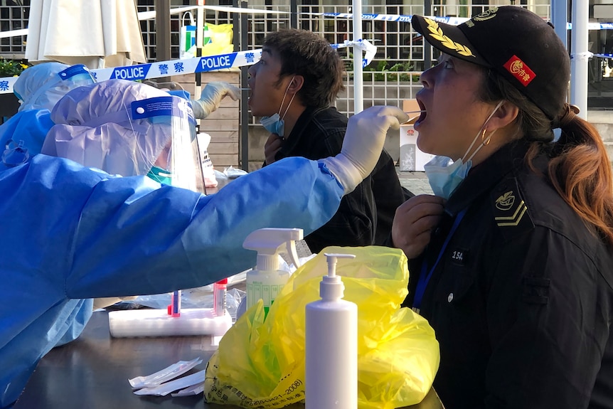 A woman is opening her mouth to do PCR test. 