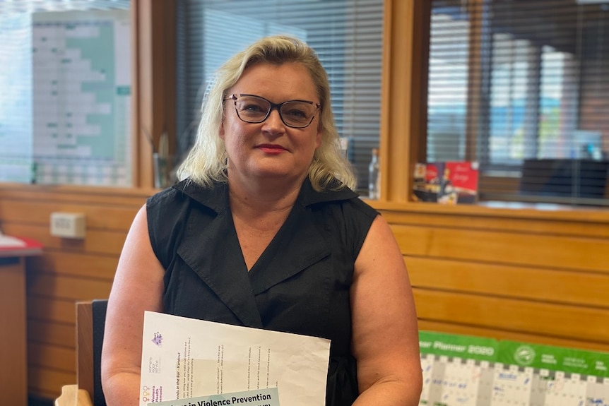 A woman sitting in an office holding some papers