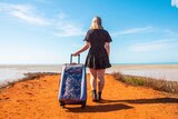 A girl stands holding a suitcase at the end of the groyne at Town Beach in Broome in a story about camping road trip tips.