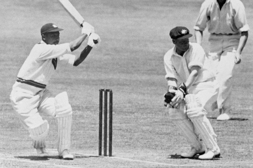 Frank Worrell barre la pelota hacia el límite mientras el portero australiano Gil Langley observa