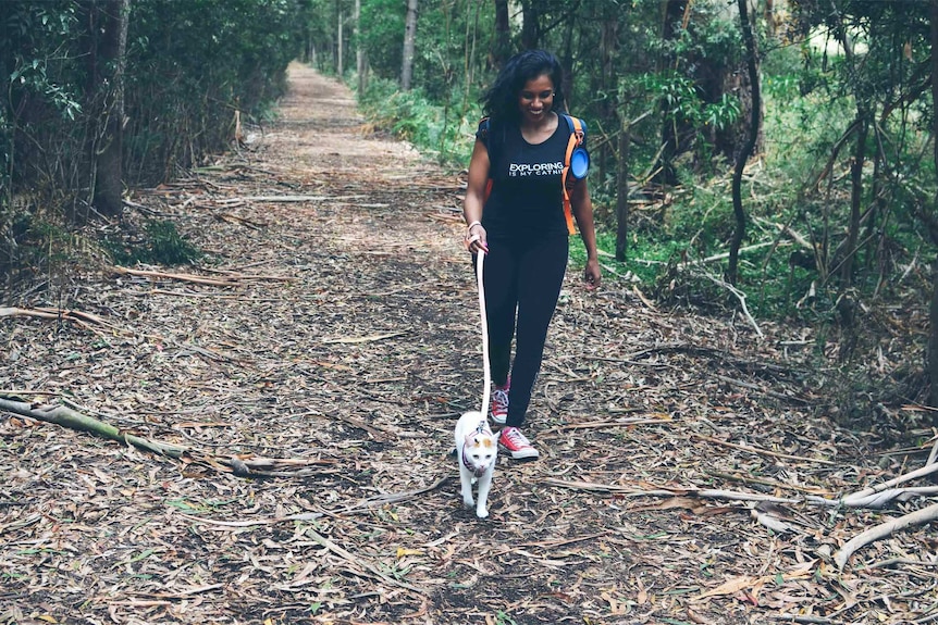 Hasara Lay walking her cat in a bush using a harness