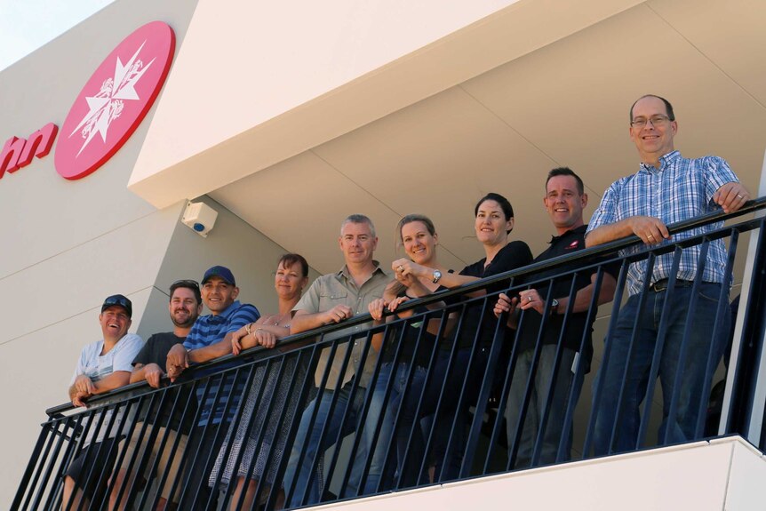 Mr Ackerman standing on a St John building balcony with his colleagues including Brendan Saich who helped save his life.