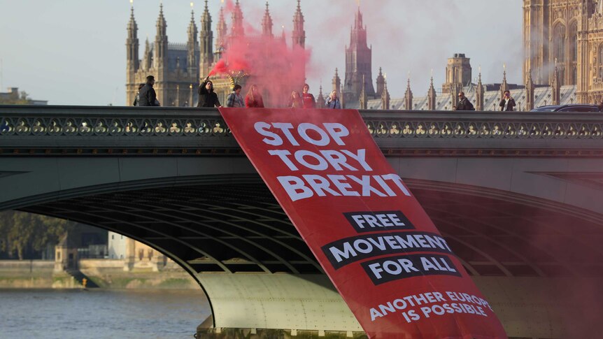 Protesters with red flares unfurl a banner saying 'Stop Tory Brexit' on Westminster Bridge in London.