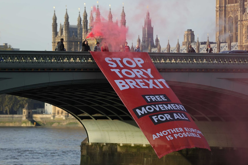 Protesters with red flares unfurl a banner saying 'Stop Tory Brexit' on Westminster Bridge in London.