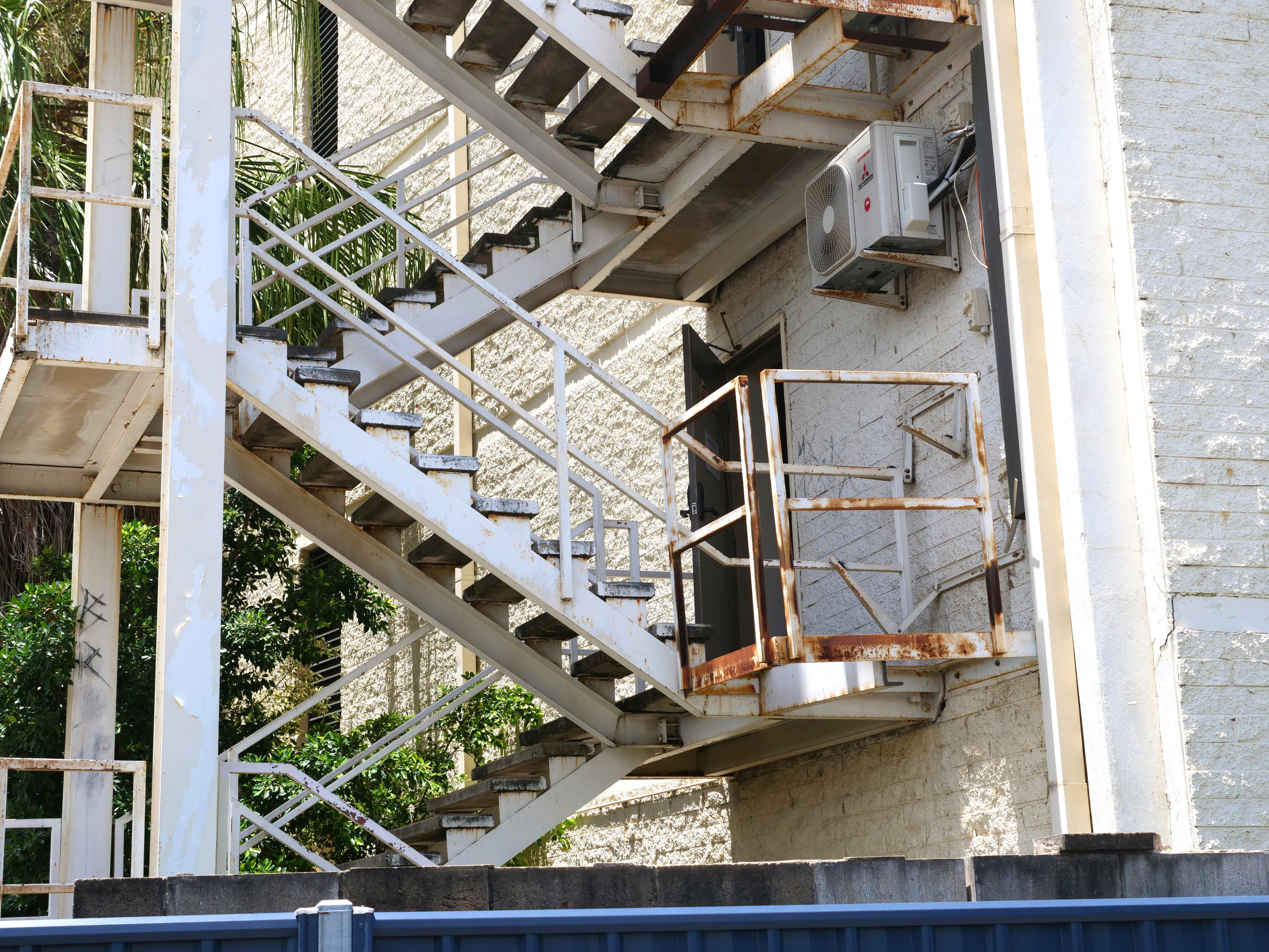 Puerta abierta contra incendios, escaleras de salida de emergencia oxidadas, edificio de hormigón