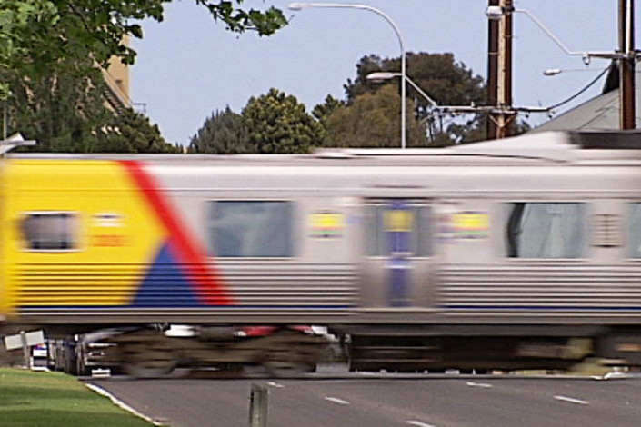 Adelaide suburban train rushes through a crossing
