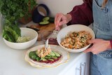Heidi Sze in her bright kitchen serving chickpea smash in a wrap, on top of beetroot hummus, lettuce and cucumber.