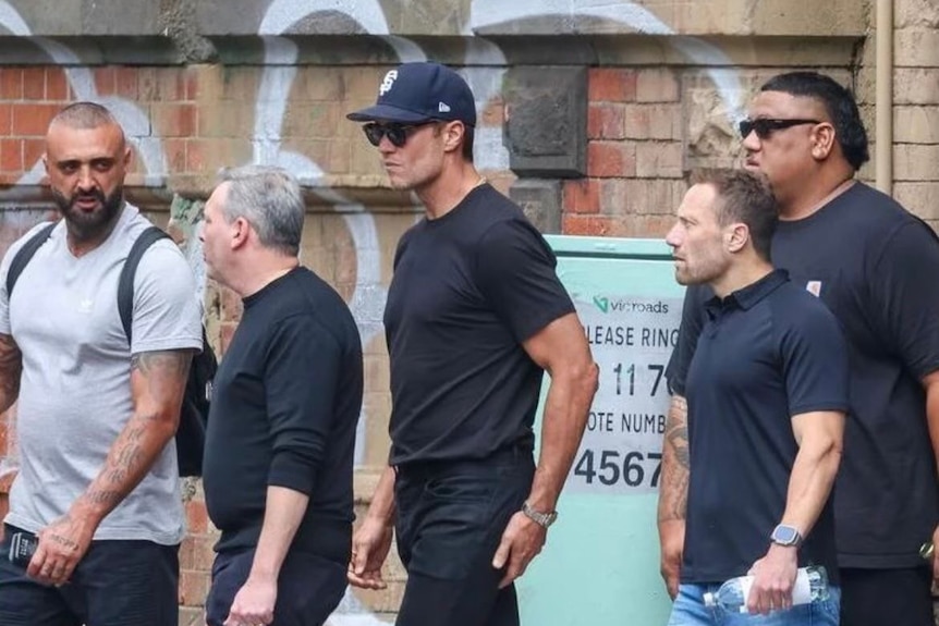 Tom Brady walking down the street with bodyguards.