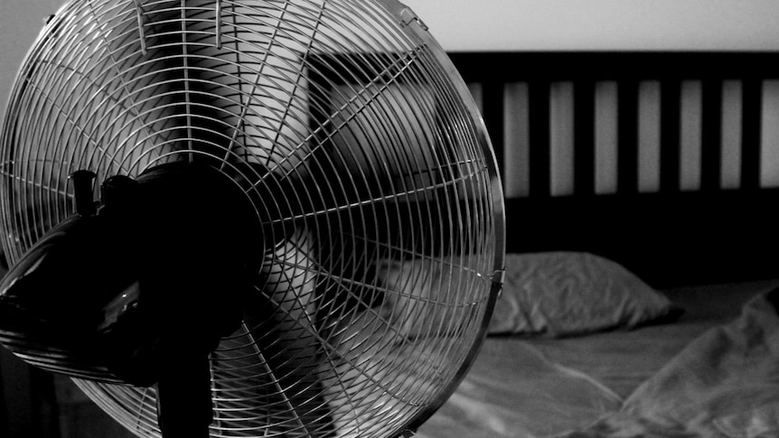 A standing fan in a bedroom