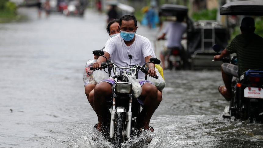 Residents on a motorcycle negotiate a flooded road due to Typhoon Molave in Vietnam.