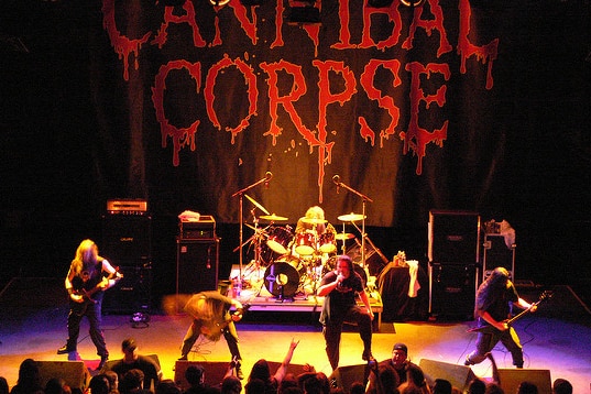 Cannibal Corpse perform on stage in front of a banner with their name on it