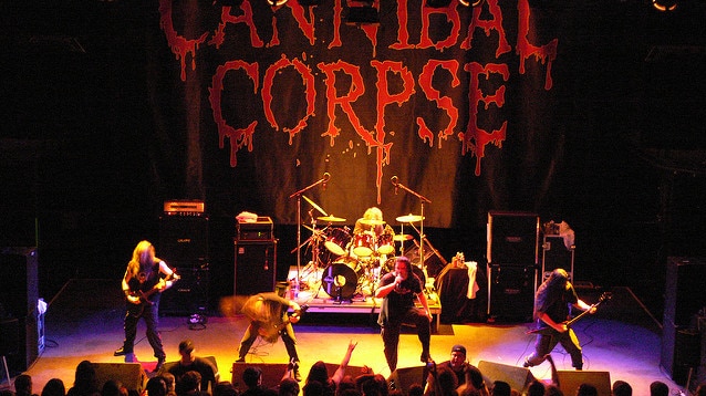 Cannibal Corpse perform on stage in front of a banner with their name on it