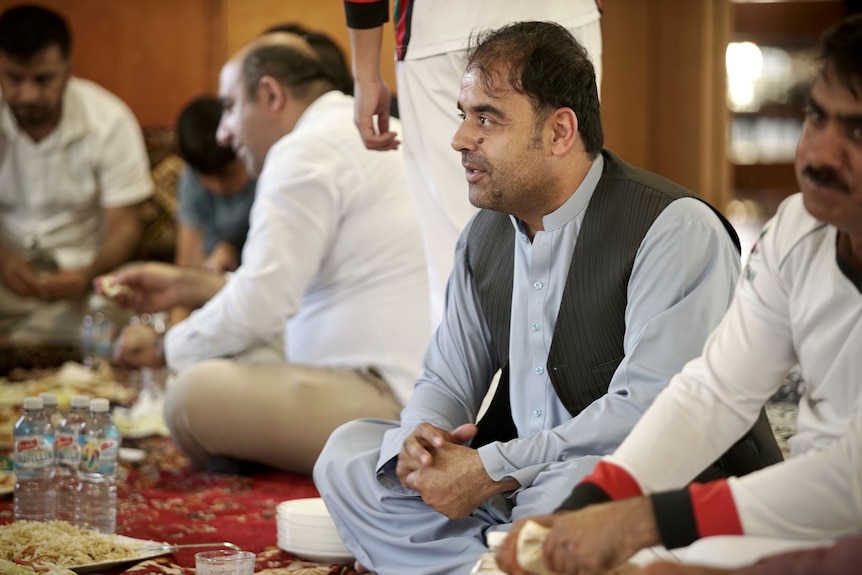 A man wearing Afghan costume sitting on carpet