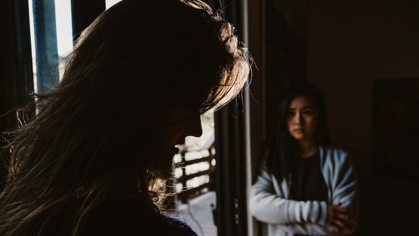 The portrait shadow of a woman's head. A second unidentified woman stands in the background.