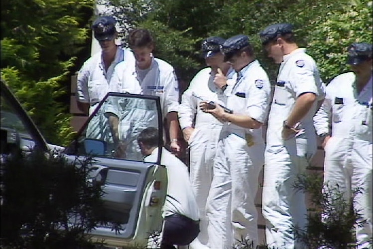 Several men in white forensics jumpsuits at the car where Colin Winchester was shot.