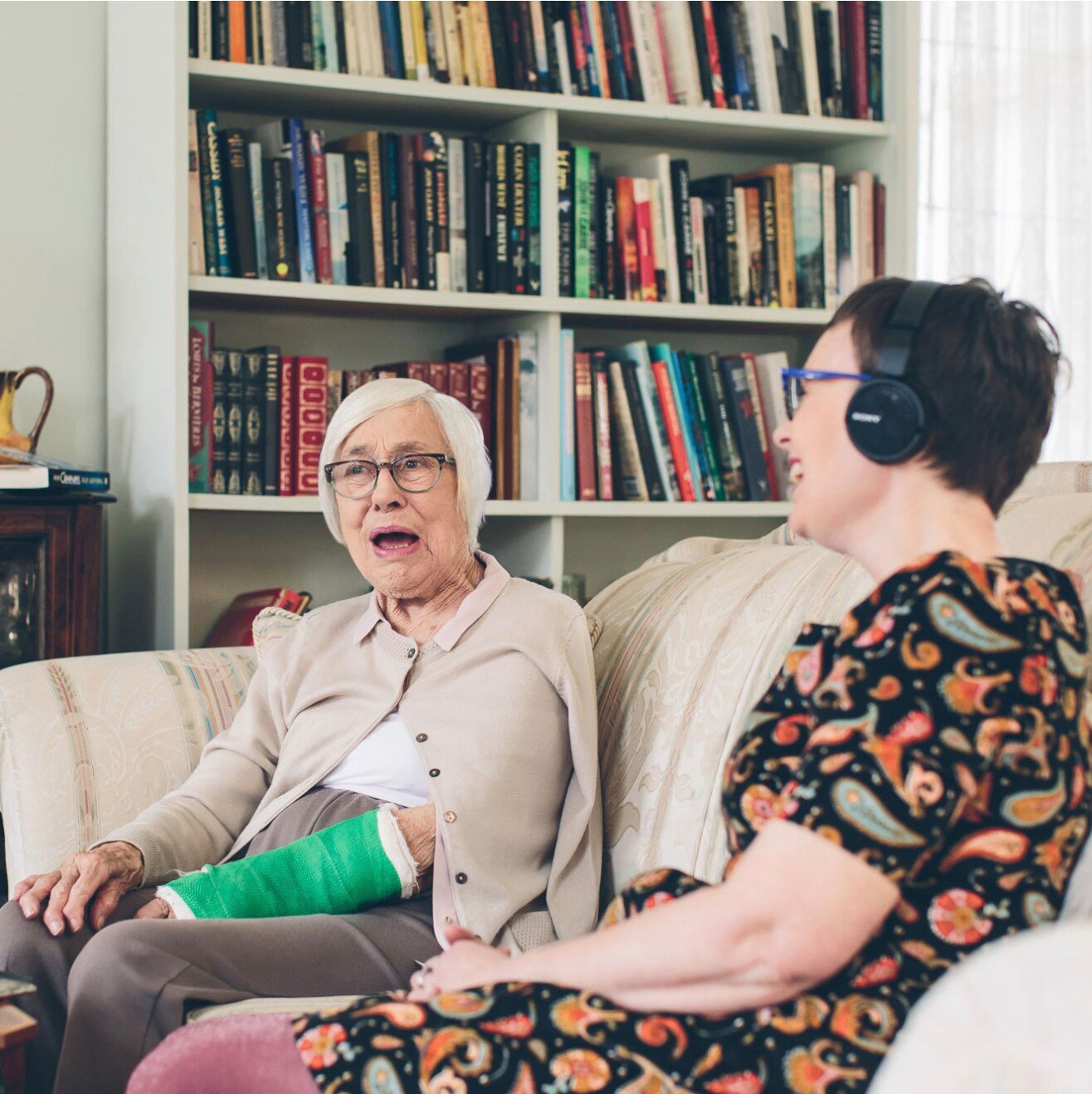 Woman in 40s and mother in 80s sitting on couch talking