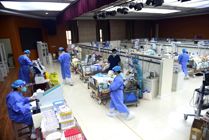 Personel medyczny zajmuje się pacjentami na oddziale intensywnej terapii, przerobionym z dużej sali konferencyjnej.