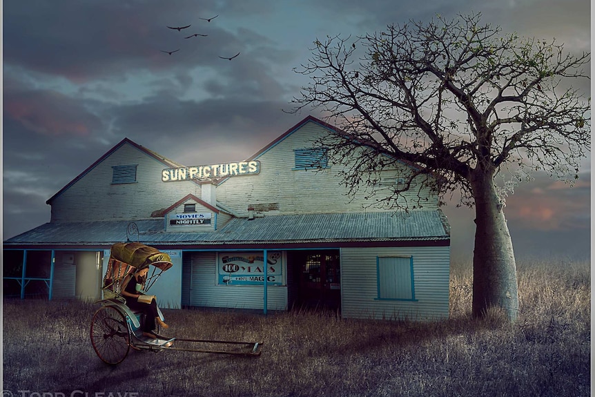 Lady sitting in cart, in front of old broome cinemas with boab tree on right.