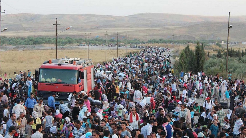 Syrians gather near the Tigris River, where they plan to cross over the border into Iraq