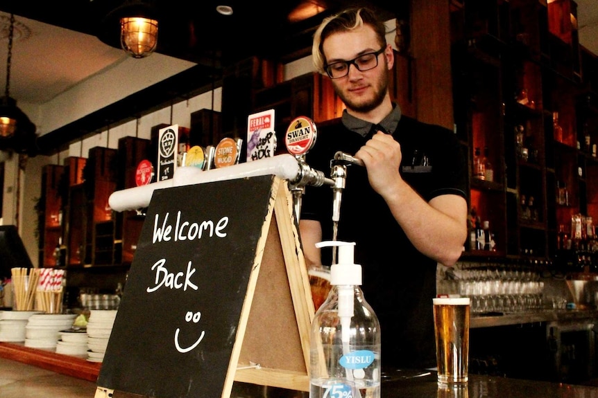 A bartender pours a beer behind a bar