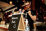A bartender pours a beer behind a bar