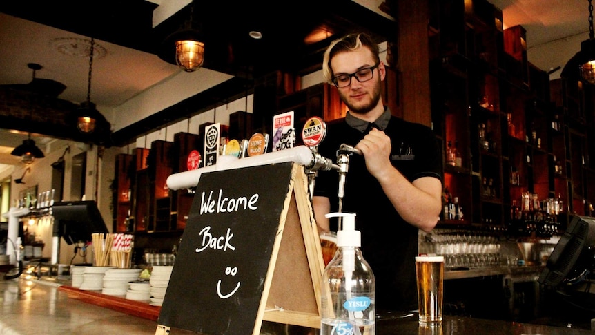 A bartender pours a beer behind a bar