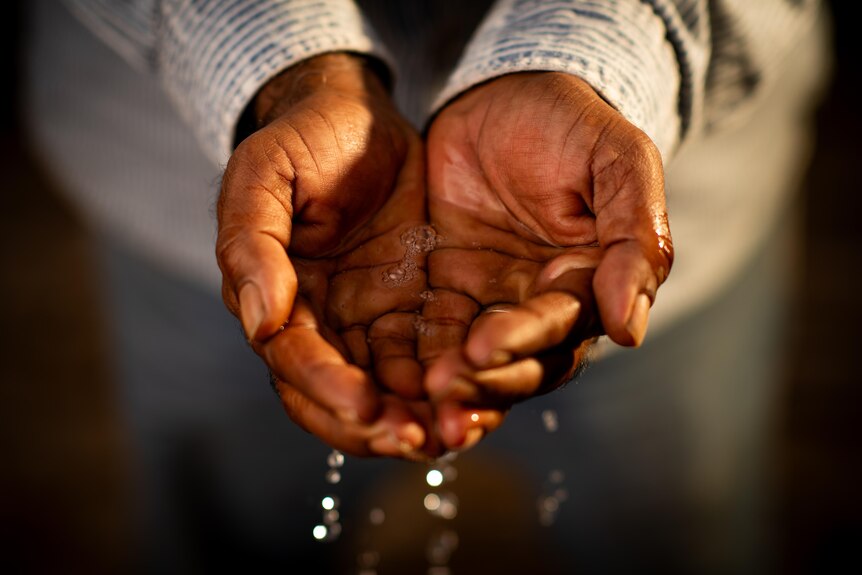 A close up of a pair of hands scooping up water