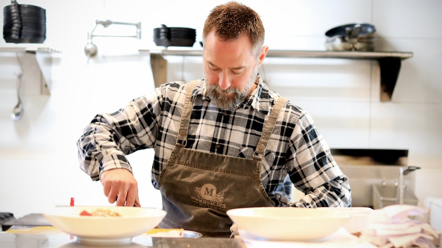 Stephen Santucci prepares food in a bowl in the kitchen of his cafe.