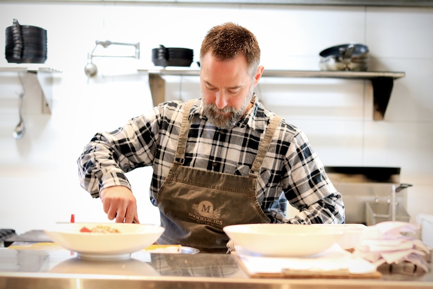 Stephen Santucci prepares food in a bowl in the kitchen of his cafe.