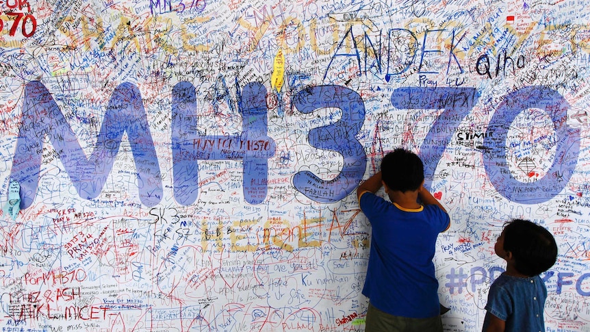 Children write well-wishes on a banner for the missing Malaysia Airlines flight MH370 at Kuala Lumpur International Airport.