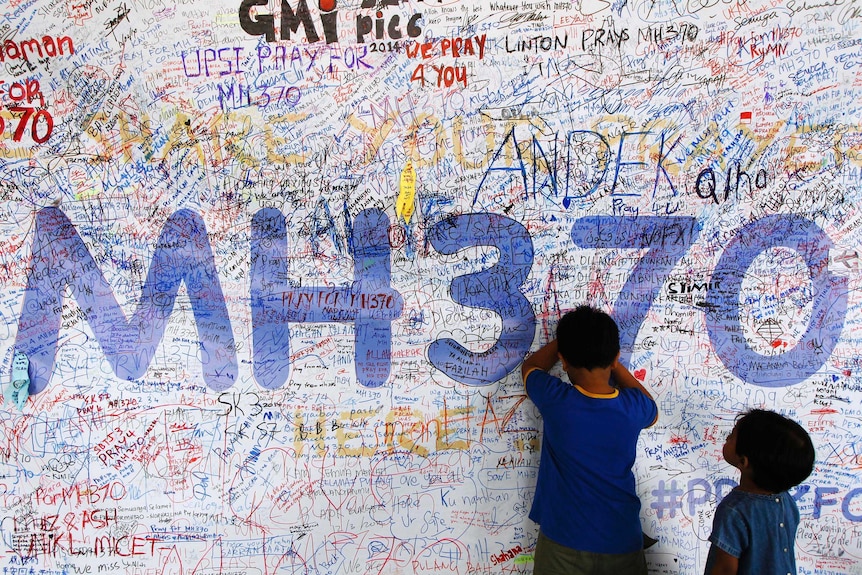 Children write well-wishes on a banner for MH370 in Kuala Lumpur.