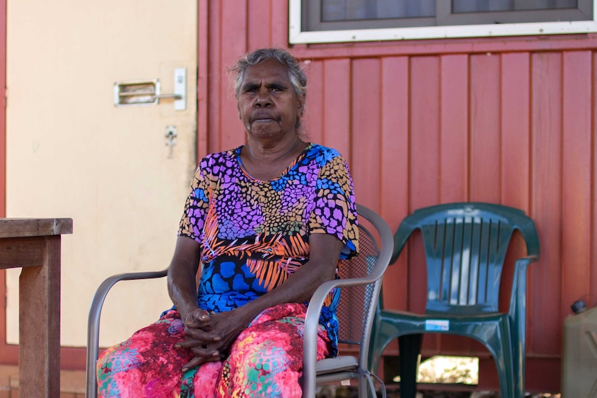 a woman in a bright top sitting in a chair.