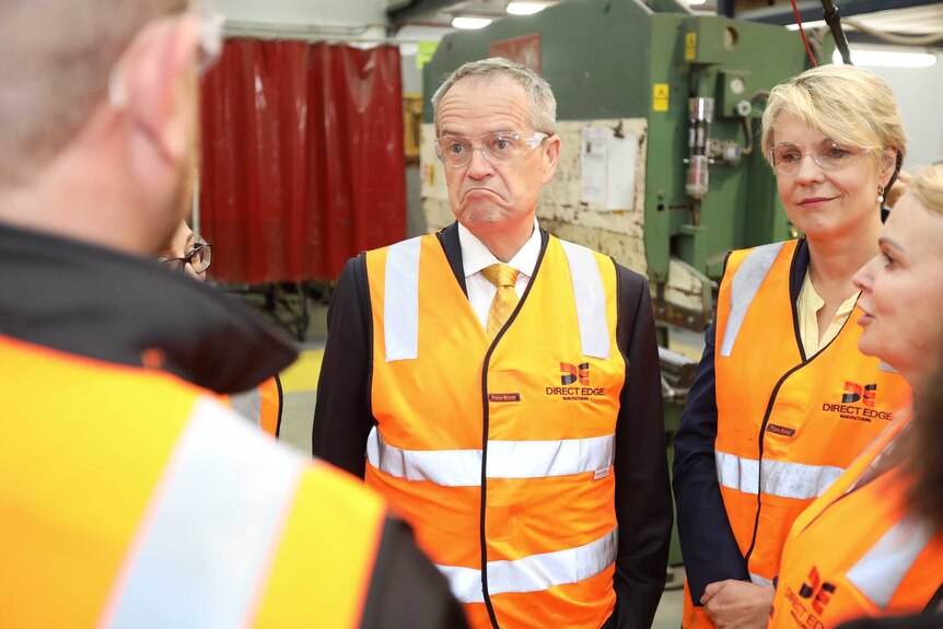 Wearing hi-vis vests and protective glasses, Bill Shorten and Tanya Plibersek meet with workers in a factory