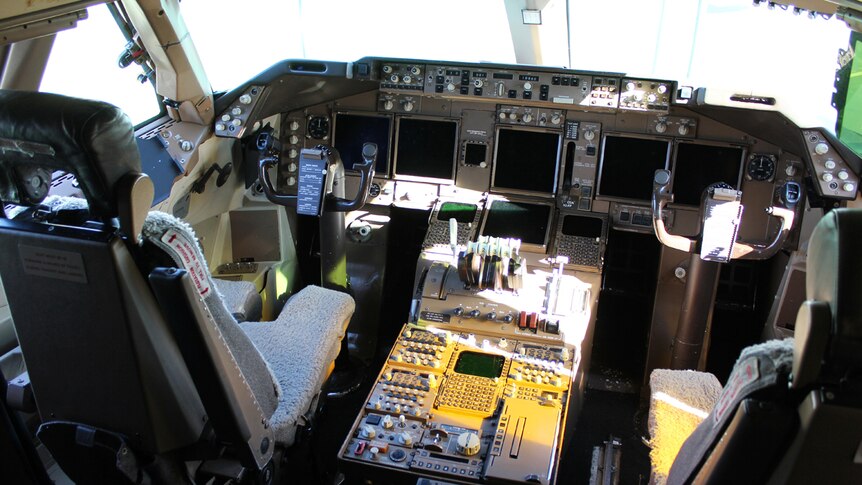 The inside of a 747 cockpit showing both pilot seats and dashboard instruments.