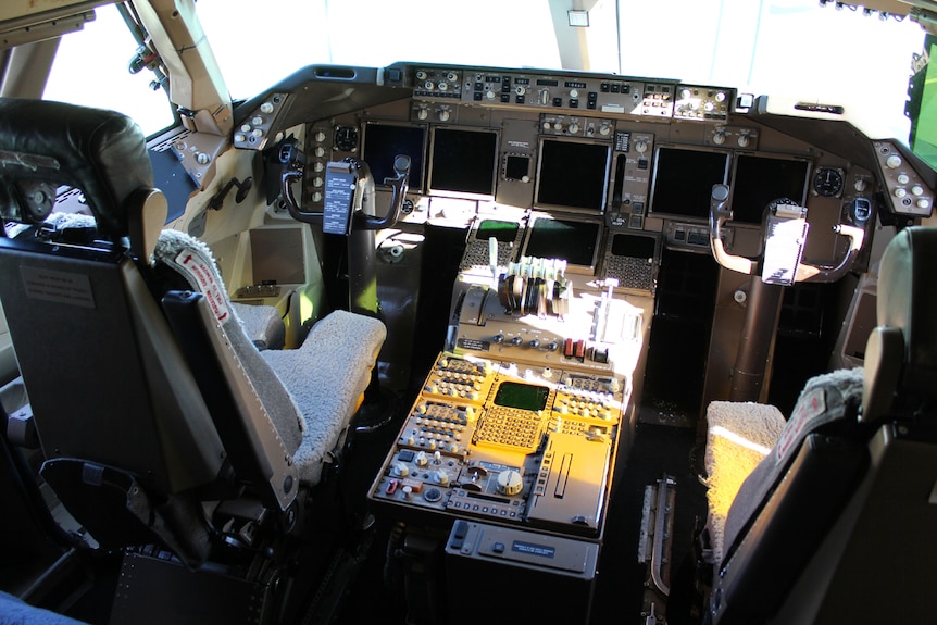 The inside of a 747 cockpit showing both pilot seats and dashboard instruments.